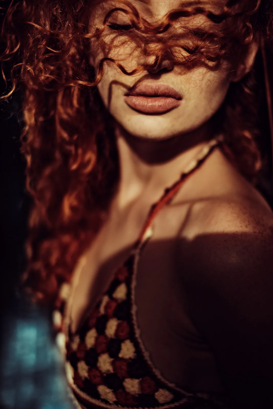 Red curls fall across the face as warm sidelight reveals the shoulder.
