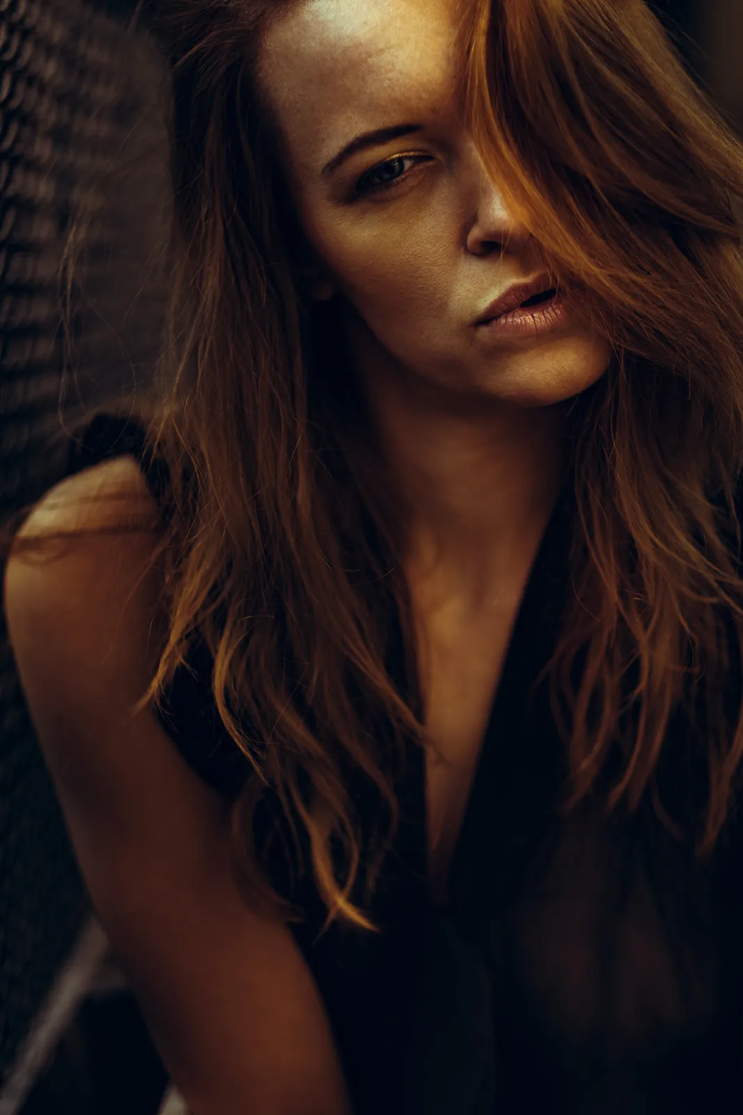 Auburn hair falls across a face turned slightly toward the camera in warm backlight.